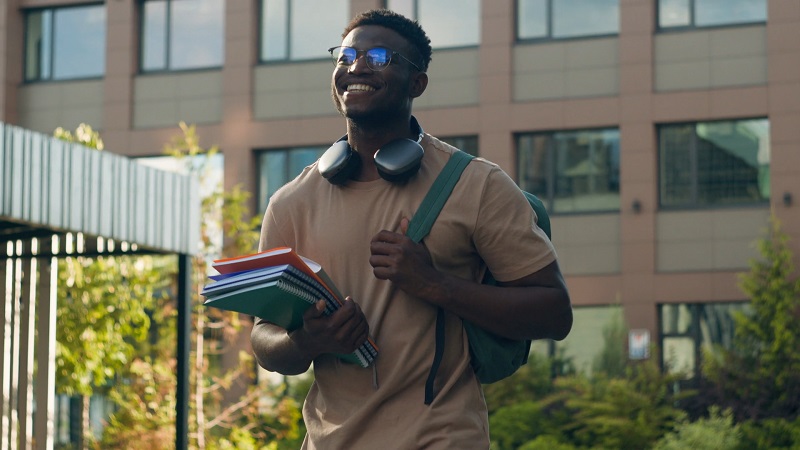 Smiling student holding notebooks outdoors, symbolizing confidence after submitting a letter of continued interest