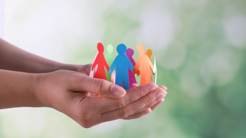 A person holds colorful paper cutouts of figures, symbolizing equity vs equality in education