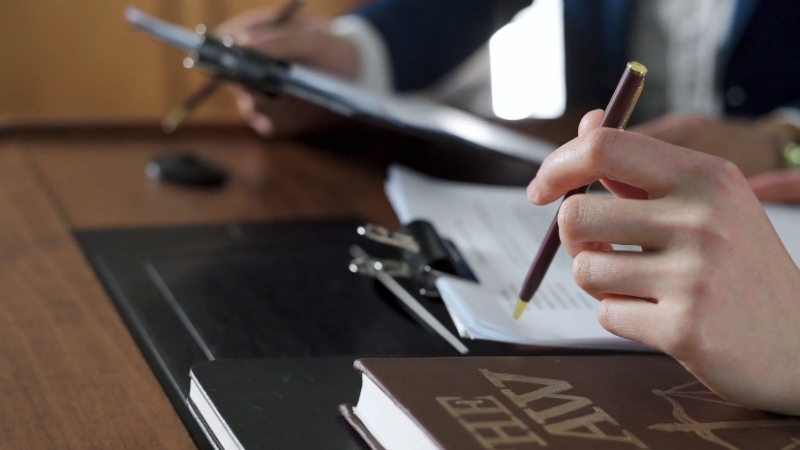 Close-up of hands reviewing legal paperwork with a law book on the desk inside a law office