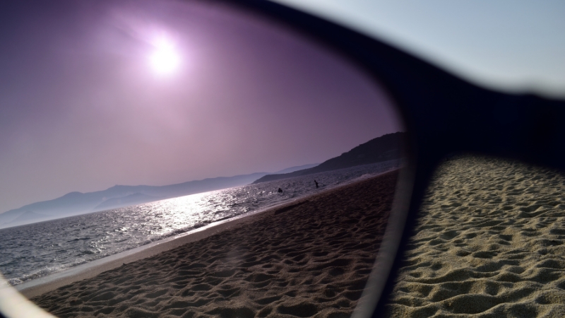 Sunglasses filter sunlight on a beach, showing physics principles of light and optics