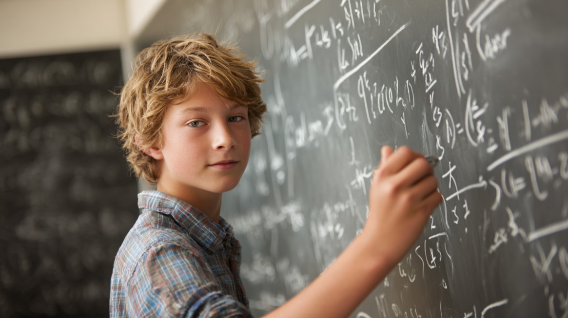 A student writing algebra equations on a chalkboard, looking confident while solving math problems