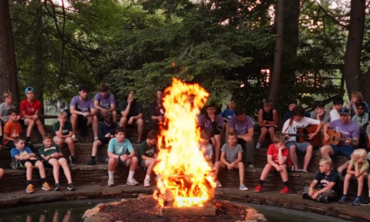 A group of kids gathered around a fire pit