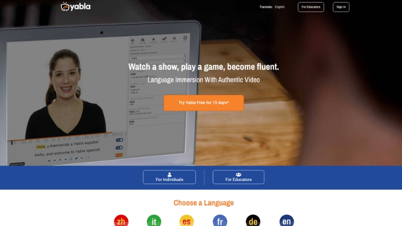 A person uses the Yabla language learning app to watch a video lesson with subtitles on a laptop