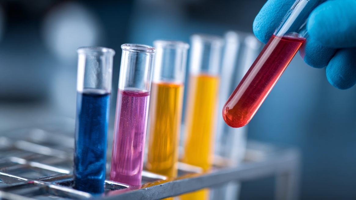 Gloved hand holding a test tube with colored samples lined up in a laboratory rack