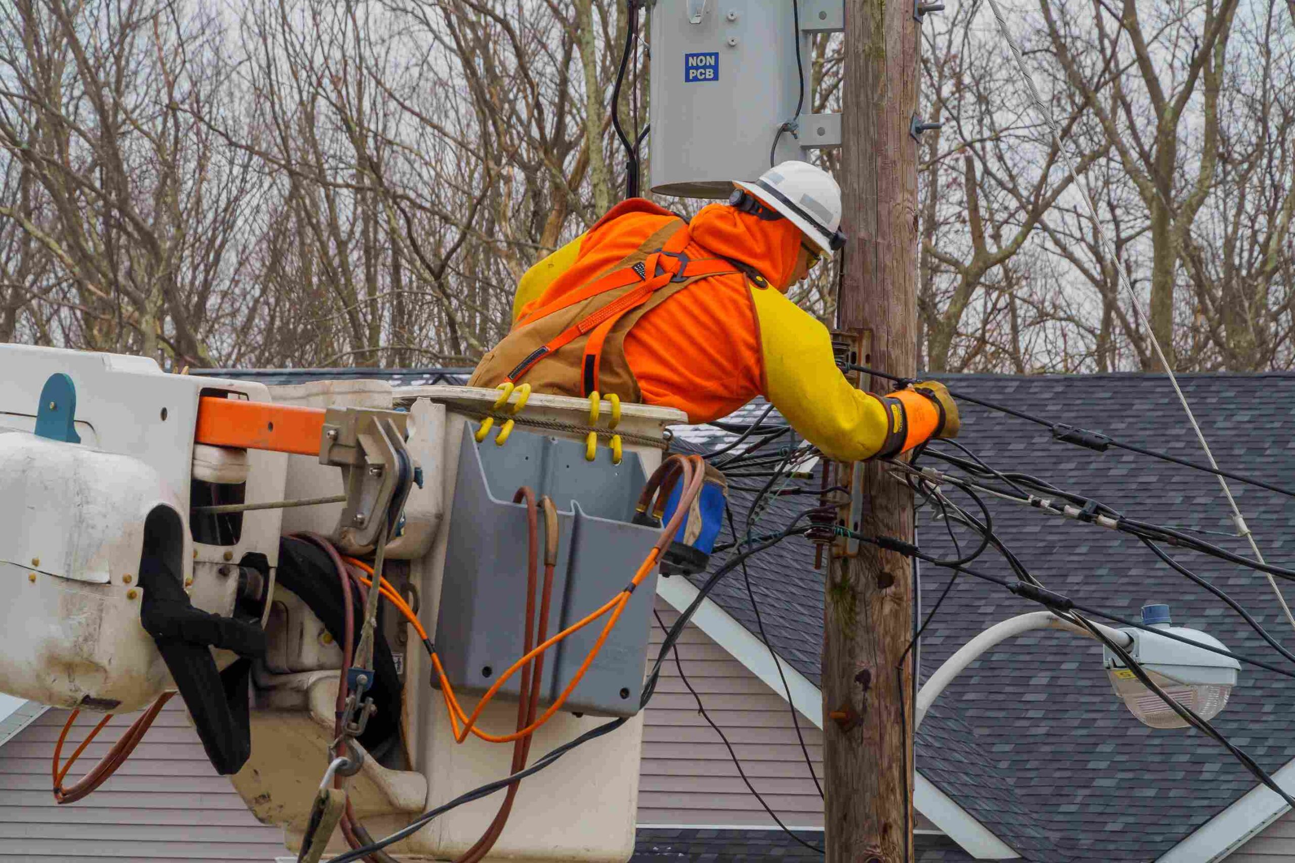 Utility worker repairing electrical power lines from a bucket truck near utility poles